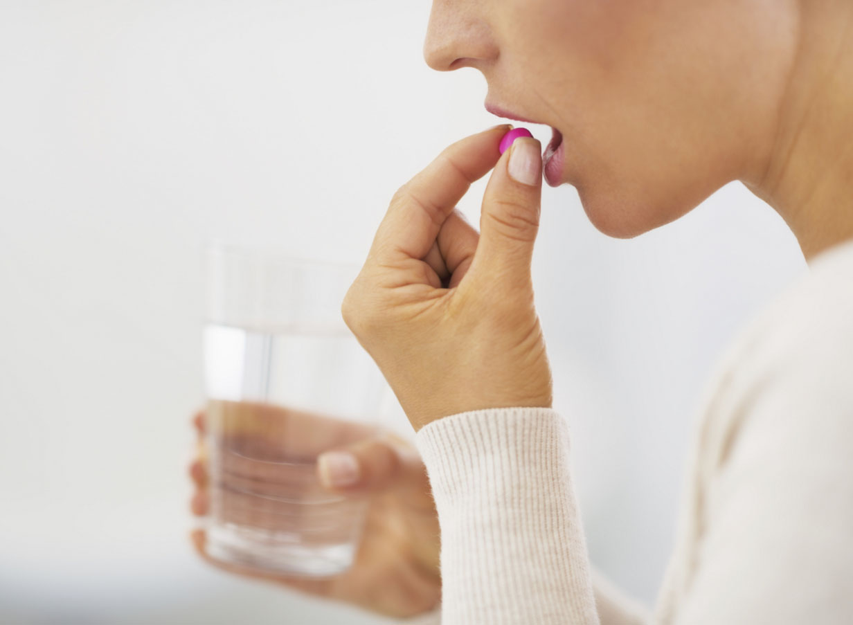 Девушка пьет таблетку