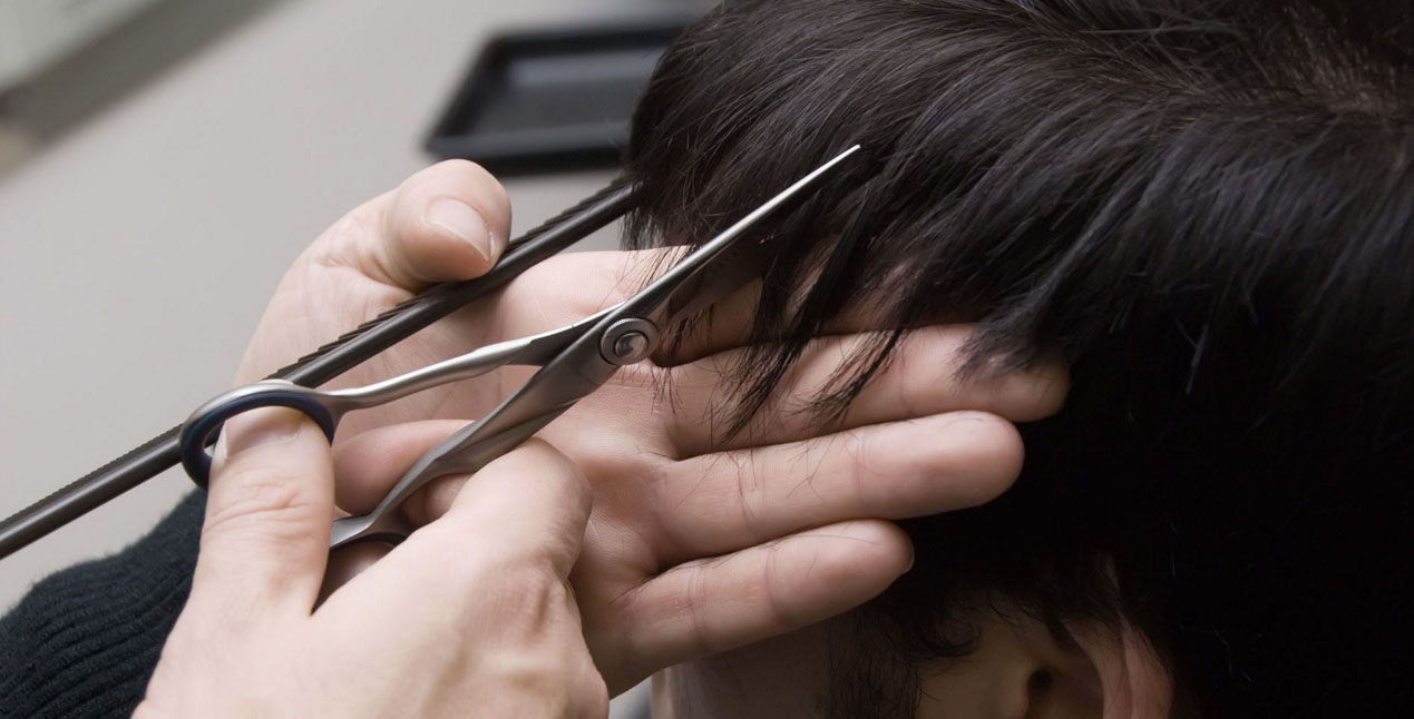 Парикмахер стрижет челку у мужчины