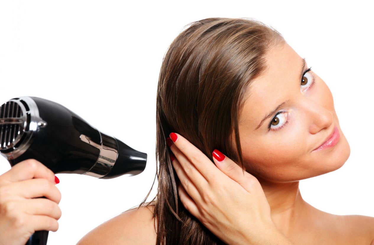 Девушка сушит волосы феном