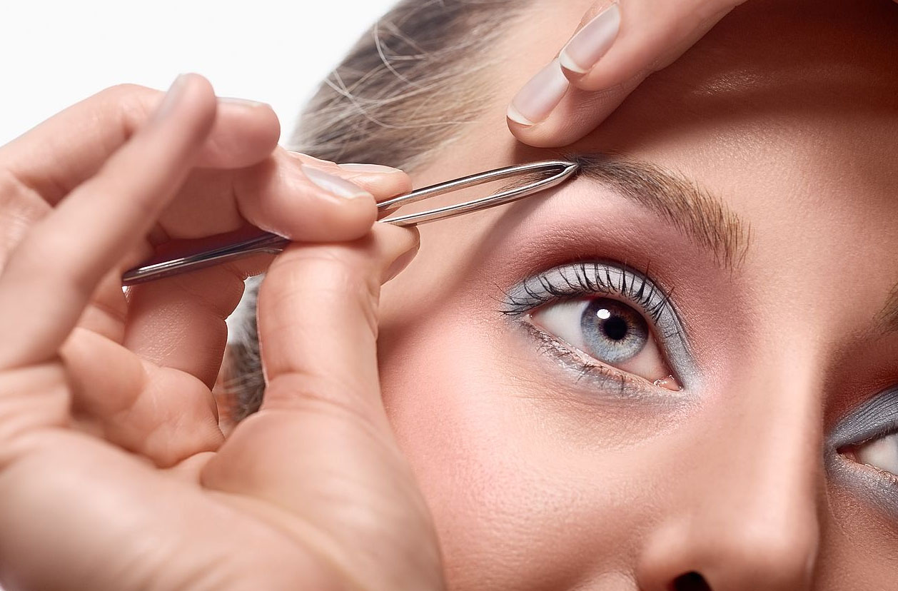 Девушка выщипывает брови